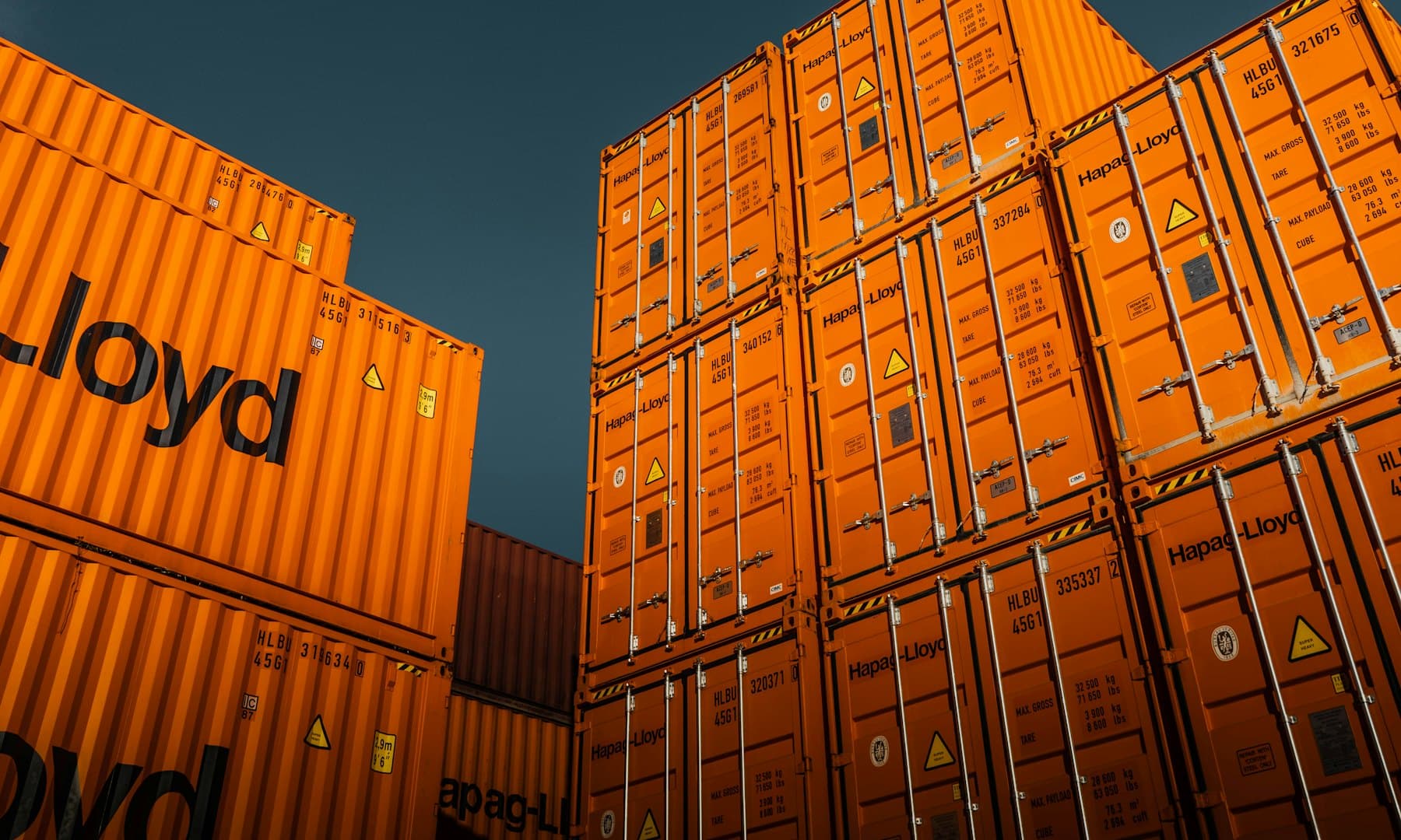 Оранжеві морські контейнери Hapag-Lloyd на тлі темного неба